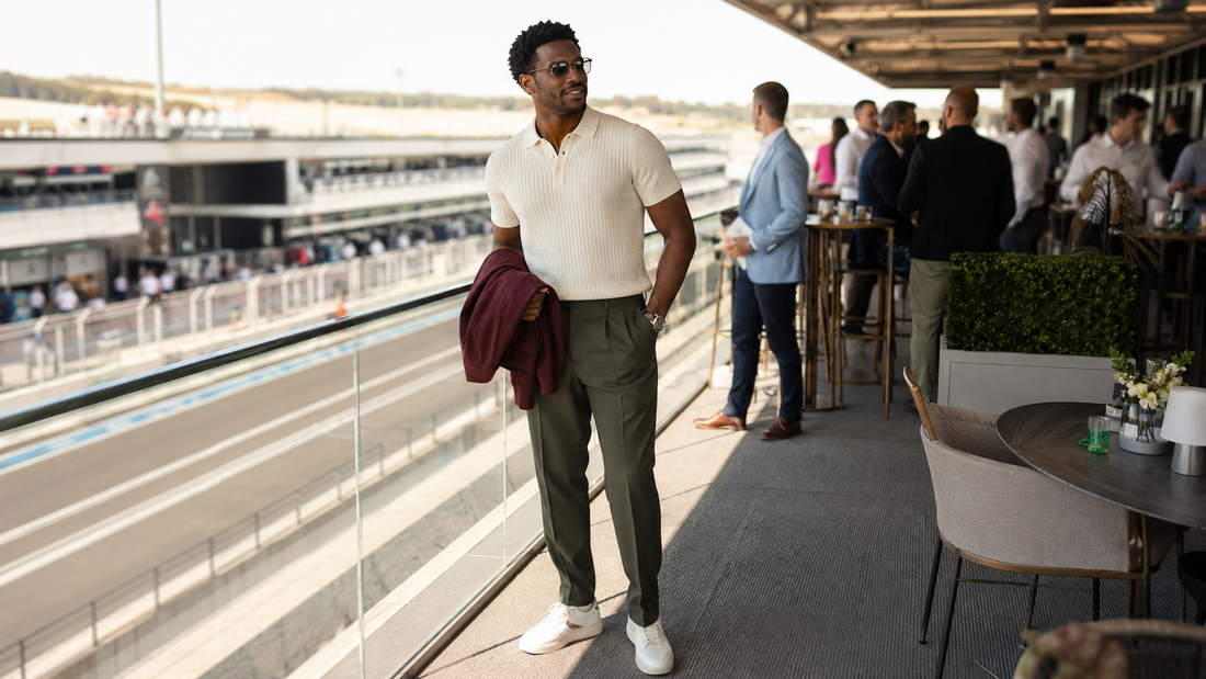 Man in a cream polo and olive trousers on a motor-racing hospitality terrace